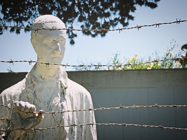 פסל של אדם העומד מאחורי גדר תיל